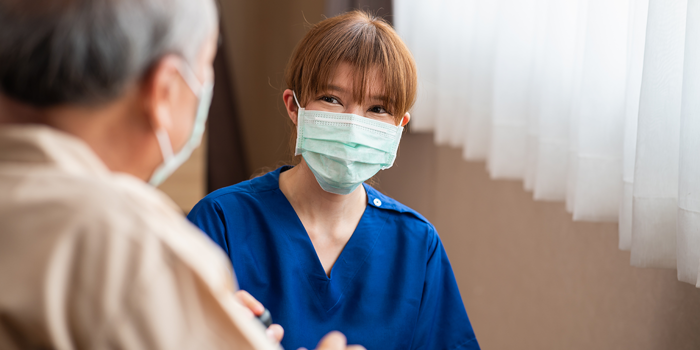 female nurse smiling conversation with patient in hospital ward