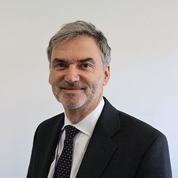 portrait of grey haired man with short beard wearing jacket and tie 