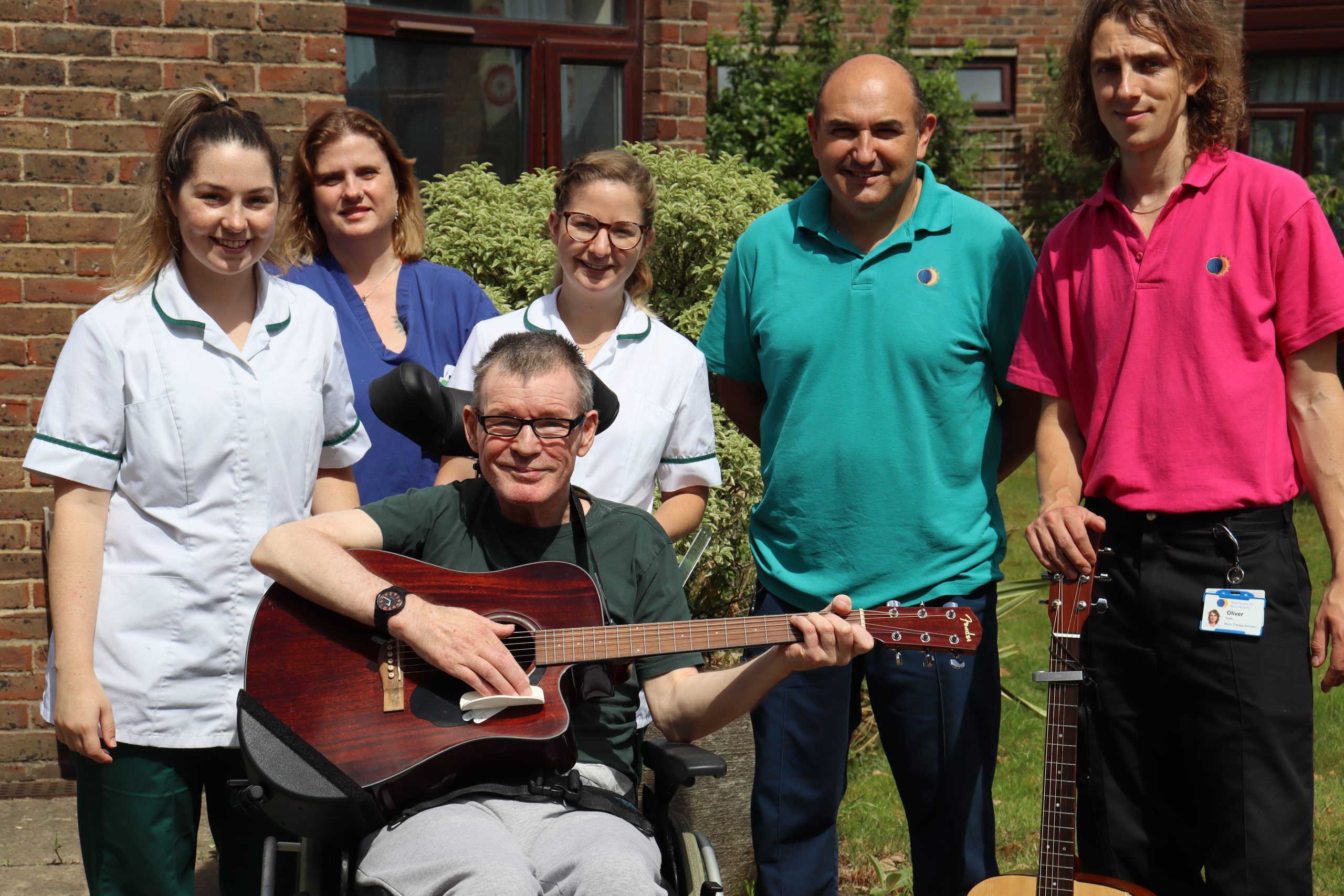 Nick holding a guitar with his therapy team